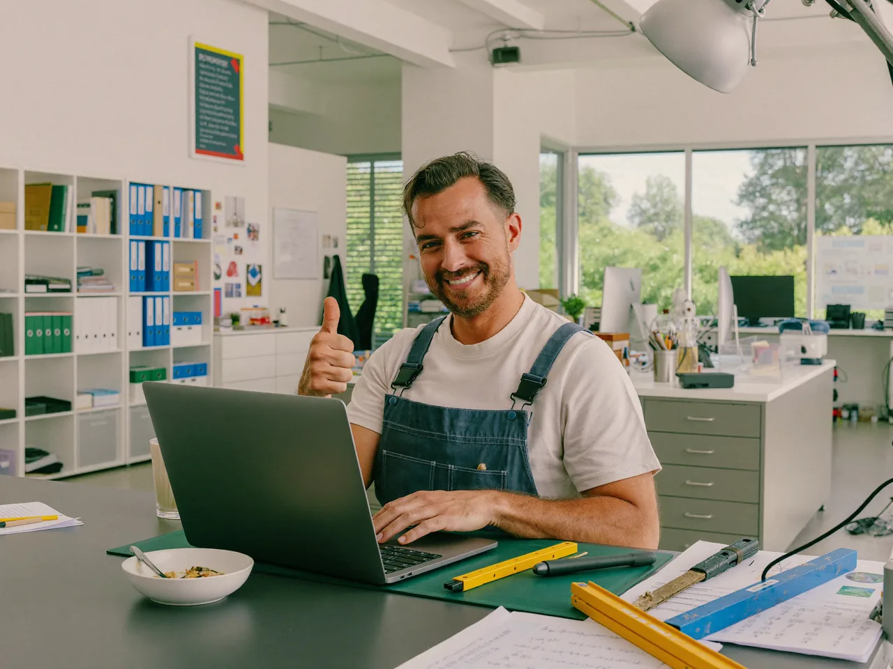 Handwerker bearbeitet zufrieden eine Anfrage am Laptop