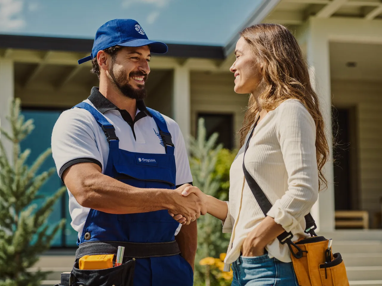 Handwerker und Kundin per Handschlag vor einem Haus